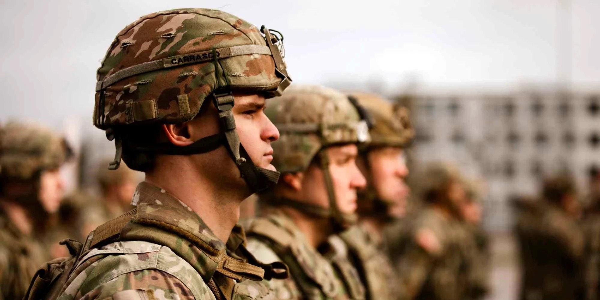 Uniformed soldiers standing in a disciplined line, photographed in profile with the nearest soldier in sharp focus