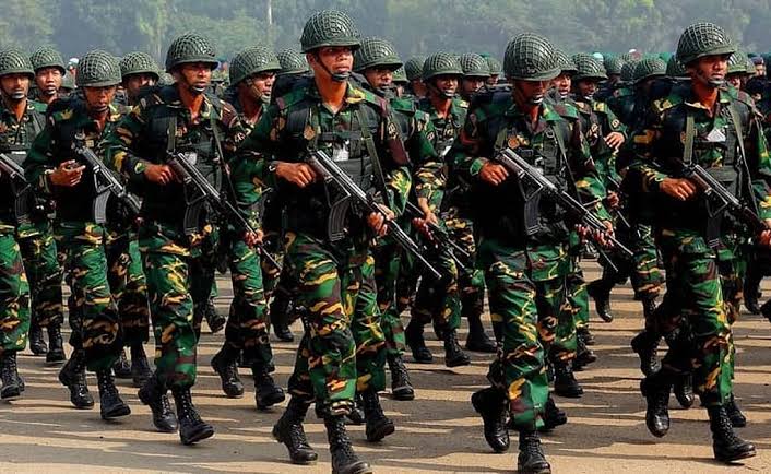 A column of soldiers in camouflage uniforms and helmets marching in step on a parade ground